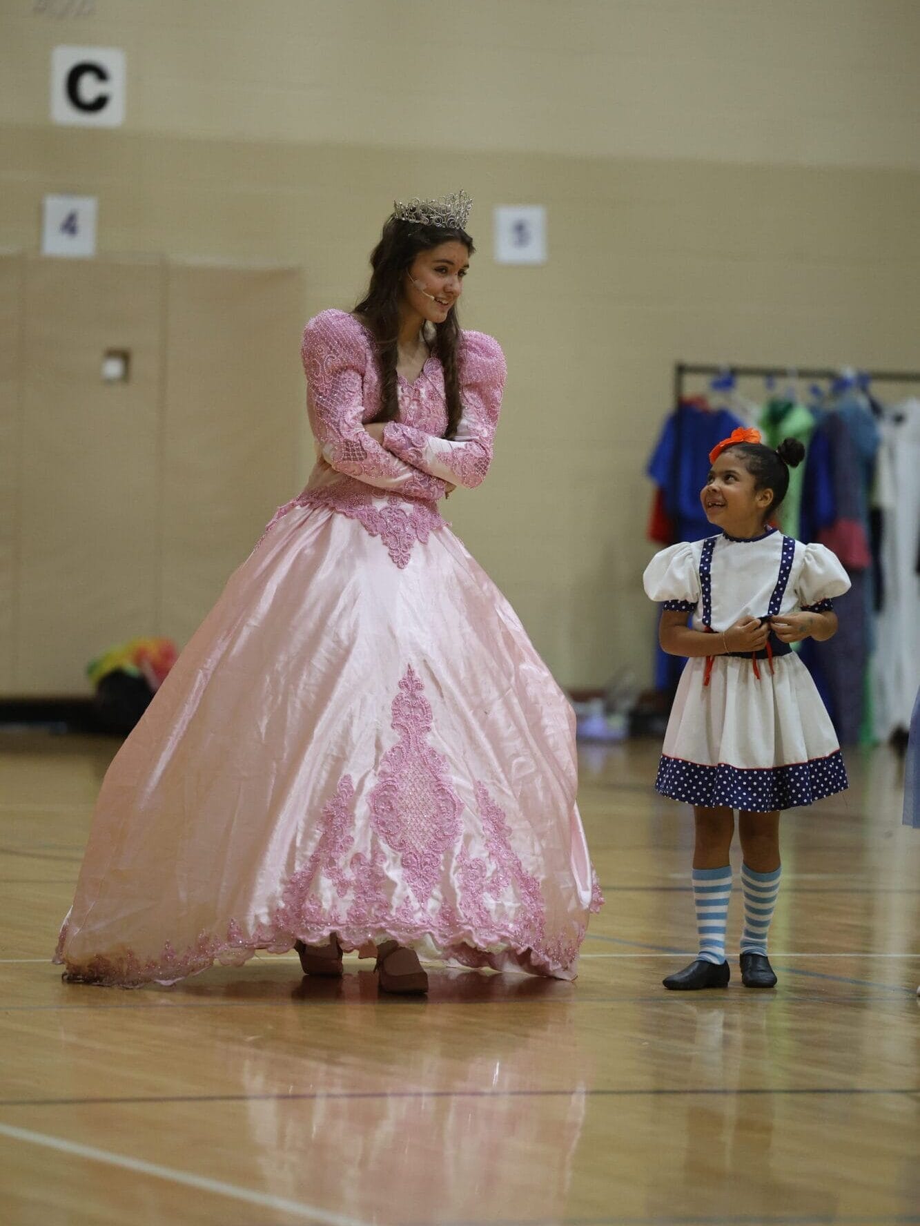 Naomi Eisenmann, dressed as Glinda the Good Witch, and first-grader Tiana Tate converse during a game of hide and seek Nov. 16, 2024, in the gymnasium at Aldo Leopold Intermediate School in between Eisenmann’s scenes in Burlington High School’s musical production of “The Wizard of Oz.”