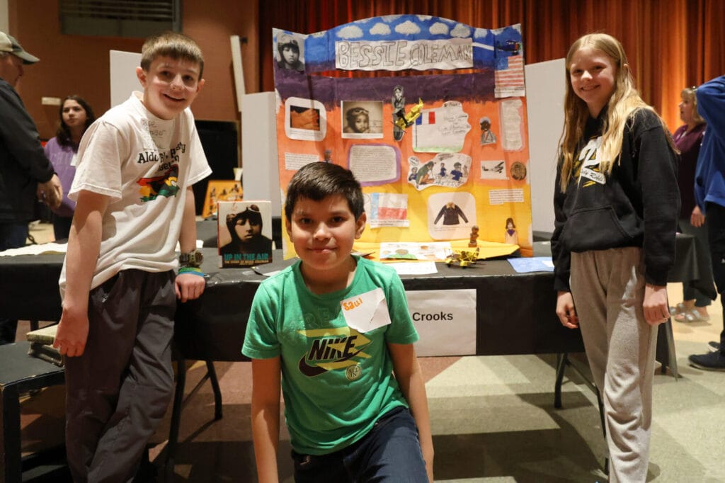 Fifth-graders Jay Sneller, Saul Rodriguez, and Delayni Mehaffy pose for a photo in front of their exhibit on Bessie Coleman, the first Black American woman to get a pilot’s license, Thursday, Feb. 27, 2025, during Aldo Leopold Intermediate School’s fourth annual Black History Museum.