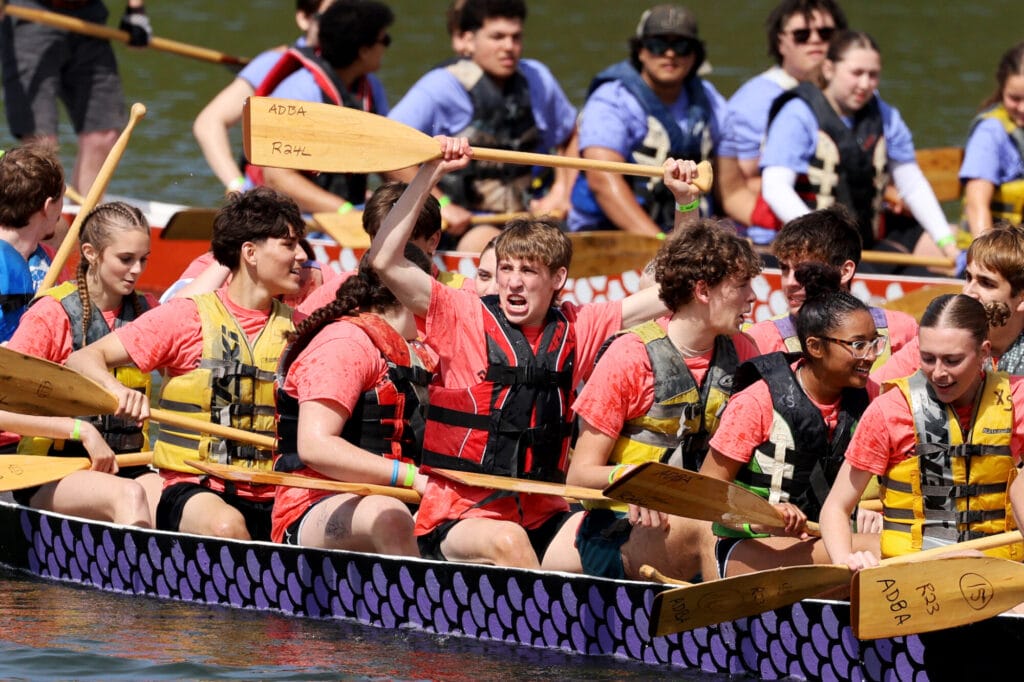 A student holds a paddle above his head while surrounded by his teammates in a proclamation of victory aboard a dragon boat Sunday, May 4, 2025, during the 34th annual Dragon Boat Races at Lake Geode in Danville. 