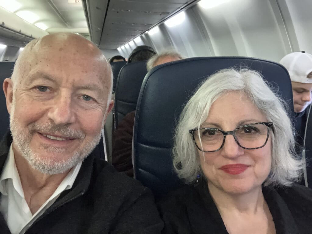 Koblar Jackson and a woman smile for a photo while seated on a plane.