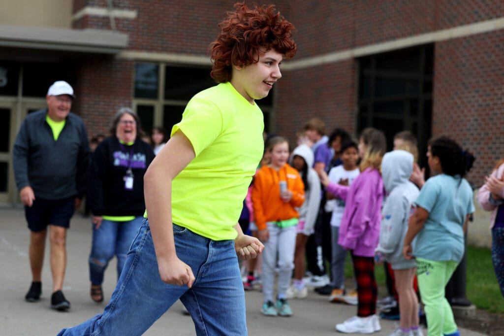 A student makes his way through a student tunnel on his way to board a bus for a state track and field competition as his coaches follow behind Thursday, May 22, 2025, outside Aldo Leopold Intermediate School.