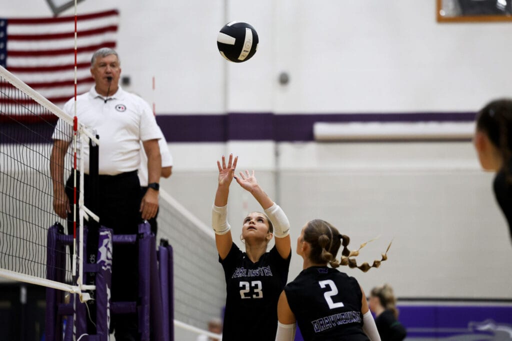 A member of the volleyball team sets the ball for her teammate to spike.